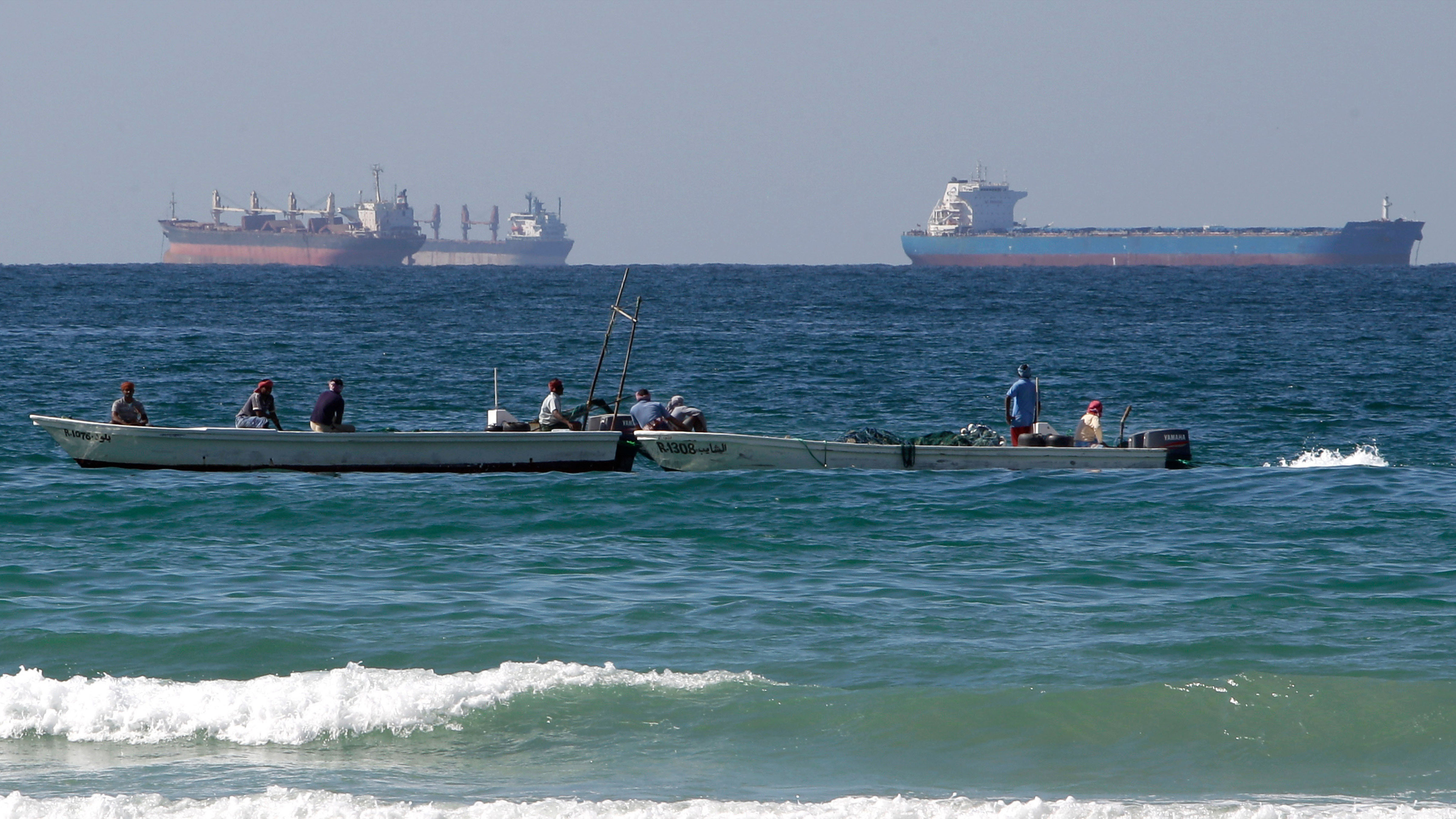 Fishermen work in front of oil tankers south of the Strait of Hormuz Jan. 19, 2012, offshore the town of Ras Al Khaimah in United Arab Emirates.