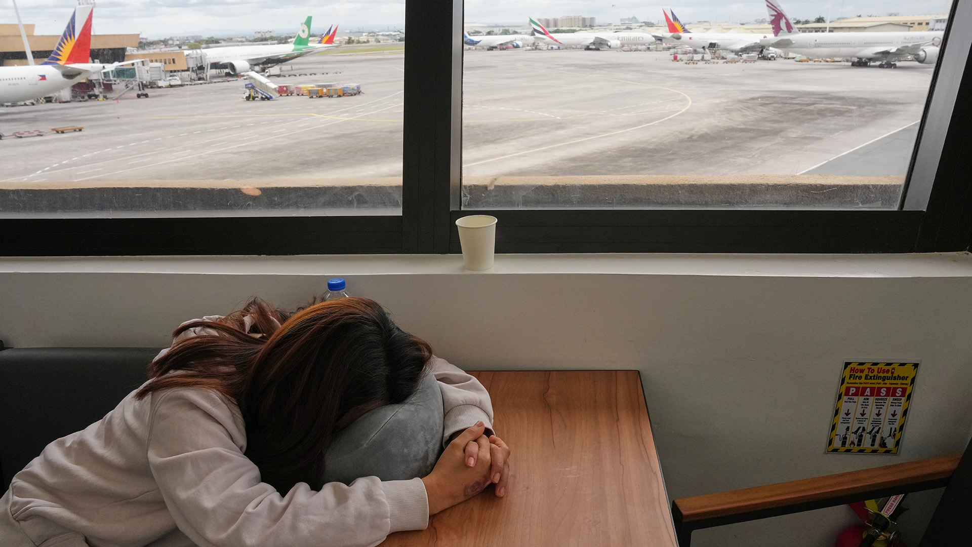 Una trabajadora filipina en el extranjero duerme mientras espera noticias de su vuelo cancelado a Oriente Medio en el aeropuerto internacional de Manila, el 2 de marzo de 2026.