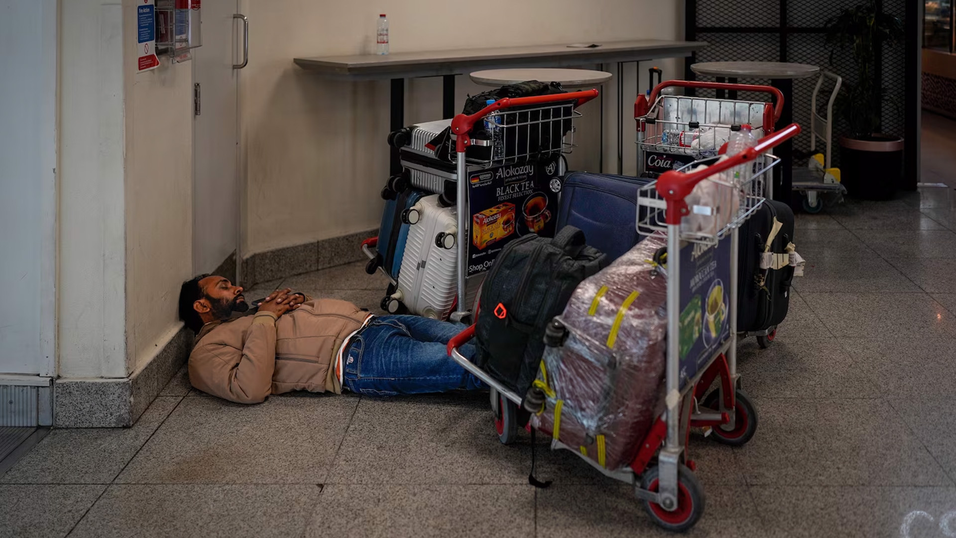 A stranded passenger sleeps on the floor outside Dubai International Airport terminal as the airport resumes limited operations in Dubai, United Arab Emirates, March 5, 2026.