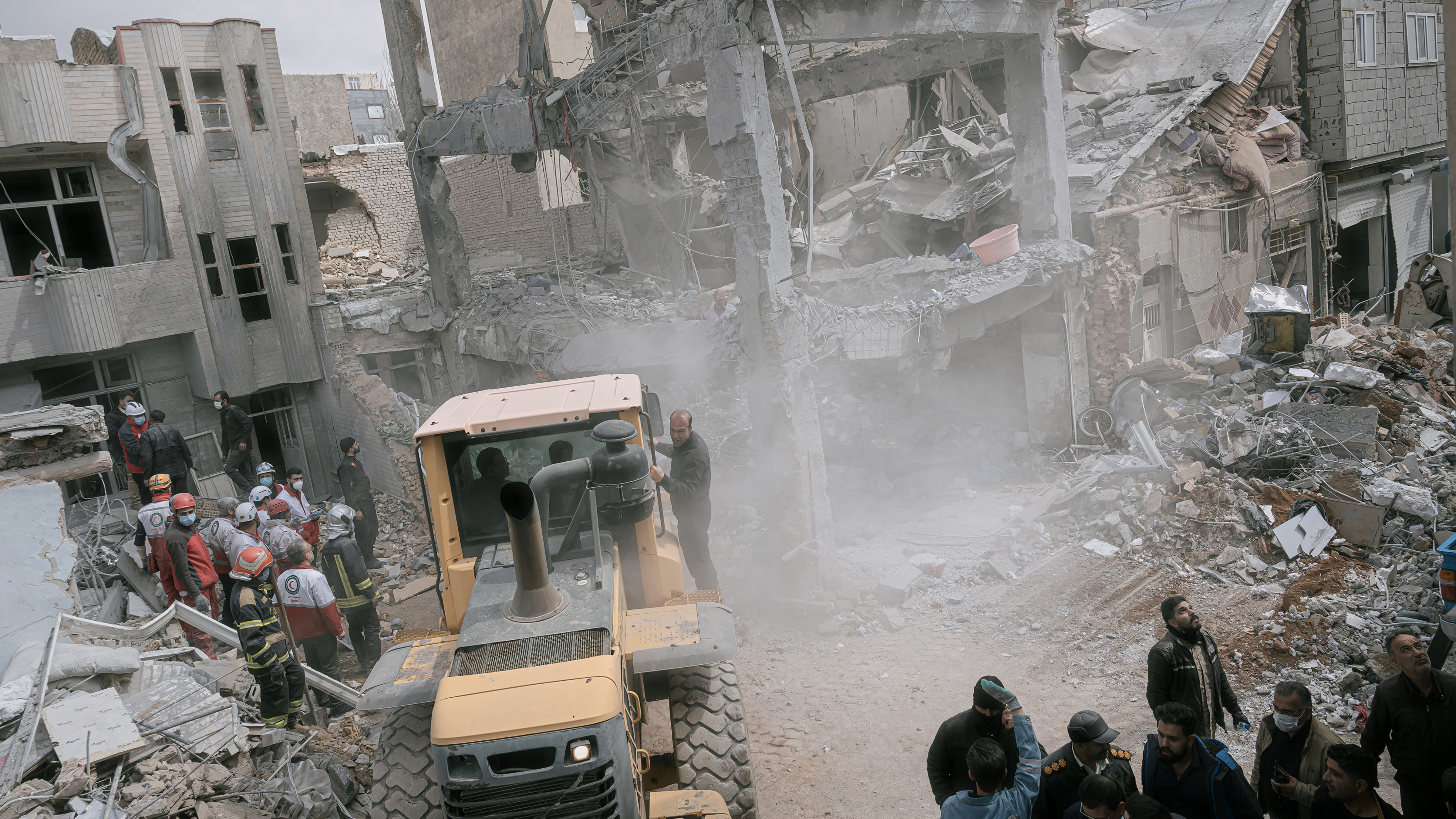 First responders clean the debris and search for victims at a residential building hit in an overnight strike during the U.S.-Israeli military campaign in Tabriz.