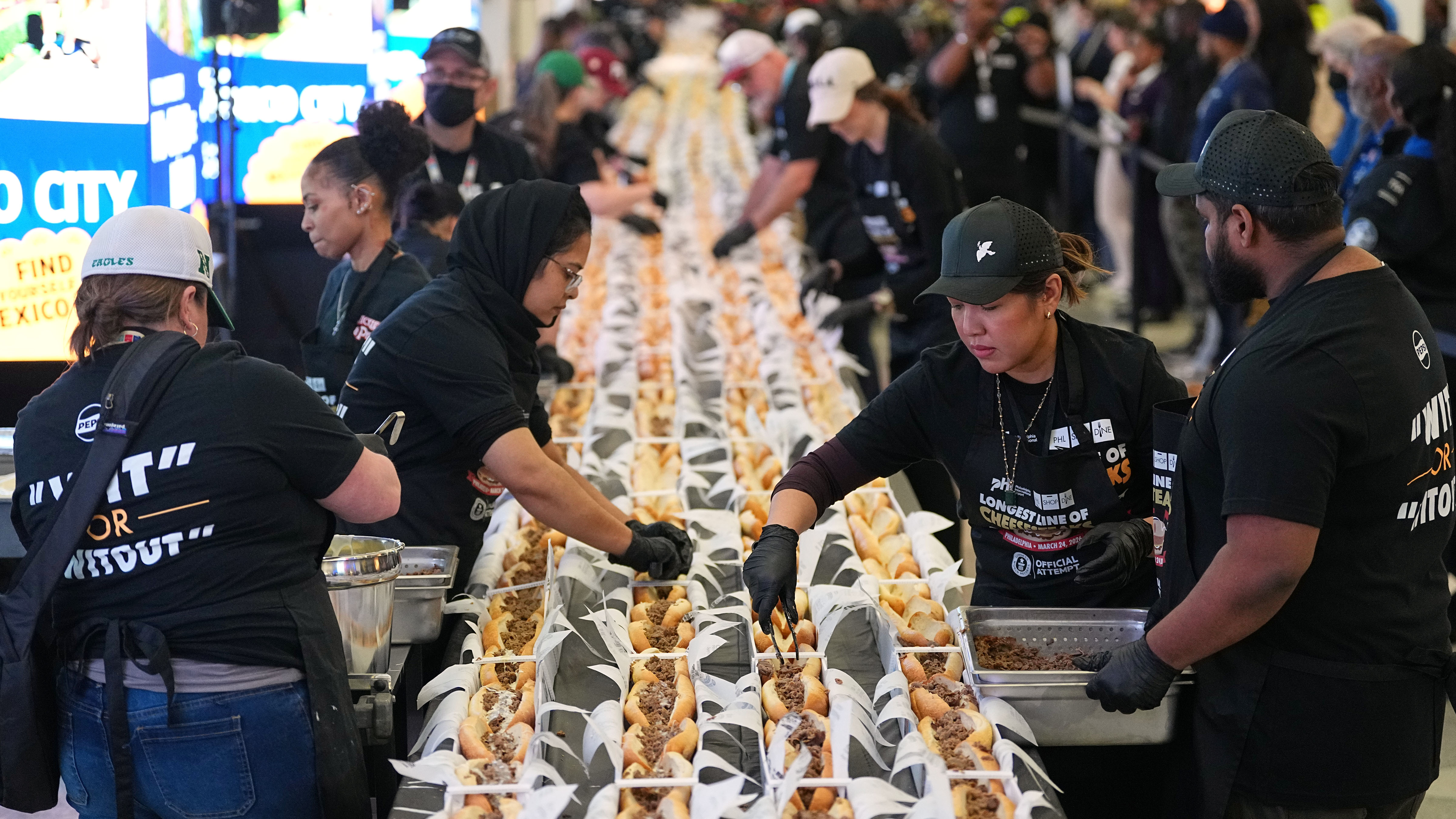 Volunteers assemble cheesesteaks in a Guinness World Record attempt on National Cheesesteak Day at Philadelphia International Airport, Tuesday, March 24, 2026, in Philadelphia.