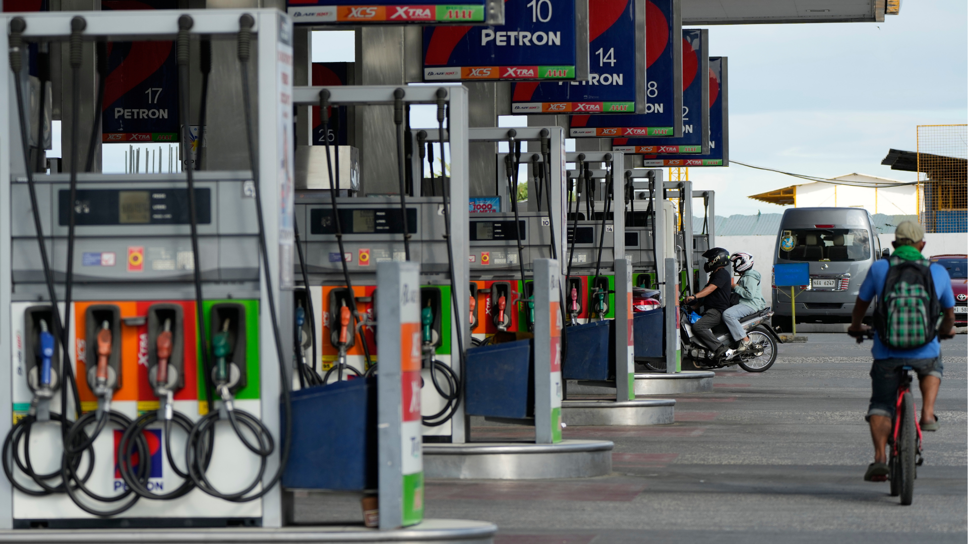 A motorcycle rider enters a gasoline station while a bicycle passes by on Wednesday, March 25, 2026, in Paranaque city, Philippines.