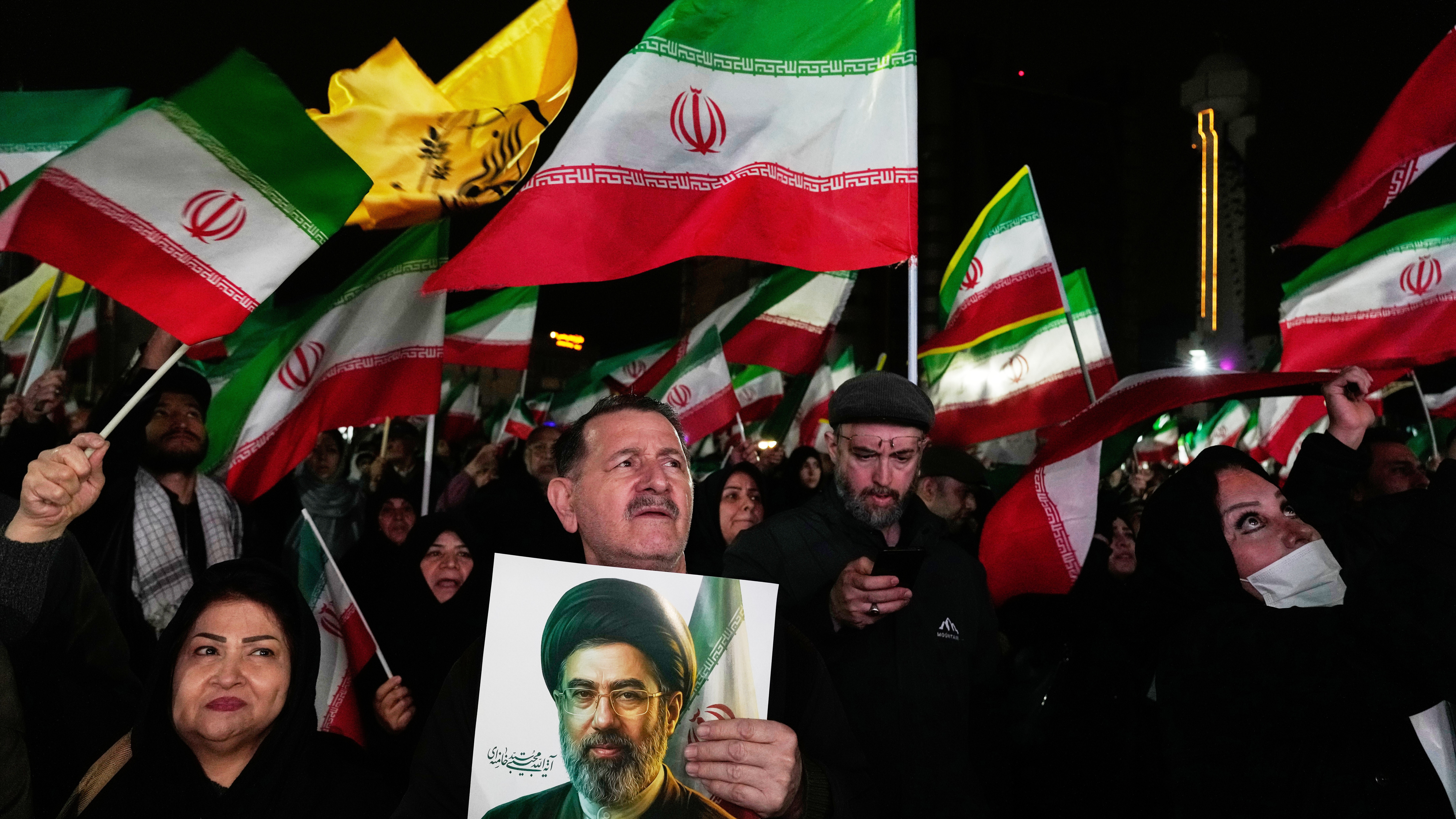 Manifestantes progubernamentales ondean banderas iraníes mientras uno sostiene una imagen del líder supremo, el ayatolá Mojtaba Jamenei, el 25 de marzo de 2026.