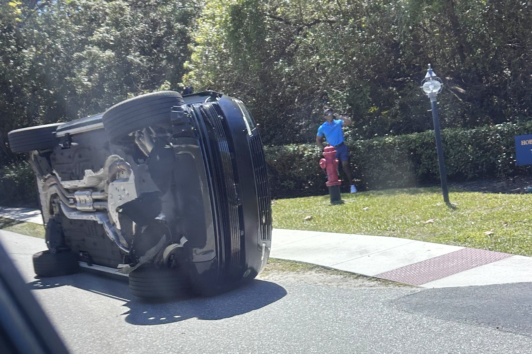 Golfer Tiger Woods stands by his overturned vehicle in Jupiter Island, Fla., on Friday, March 27, 2026.