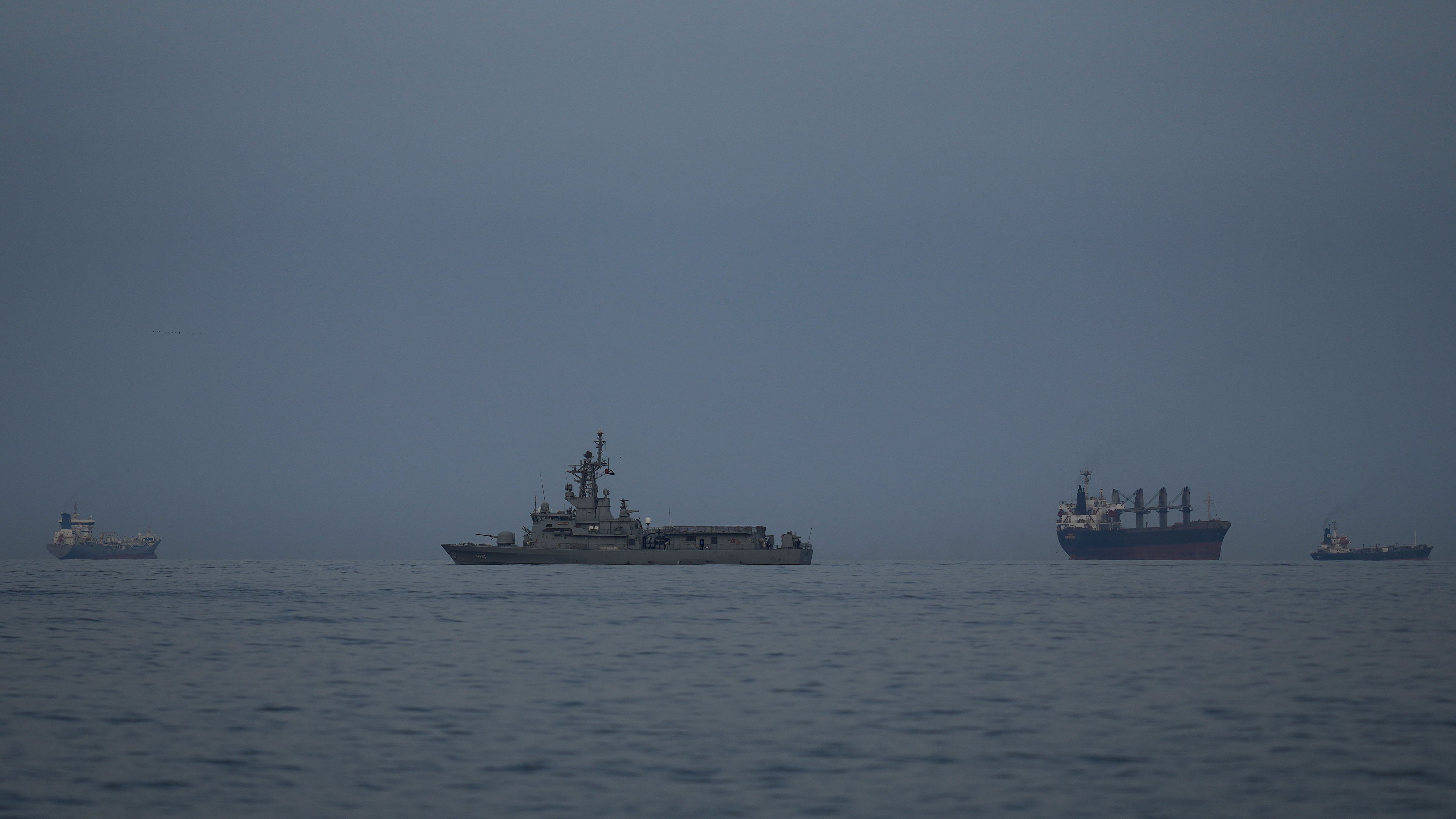 A UAE navy vessel patrols next to cargo ships and oil tankers in the Strait of Hormuz as seen from Khor Fakkan, United Arab Emirates, Wednesday, March 11, 2026.