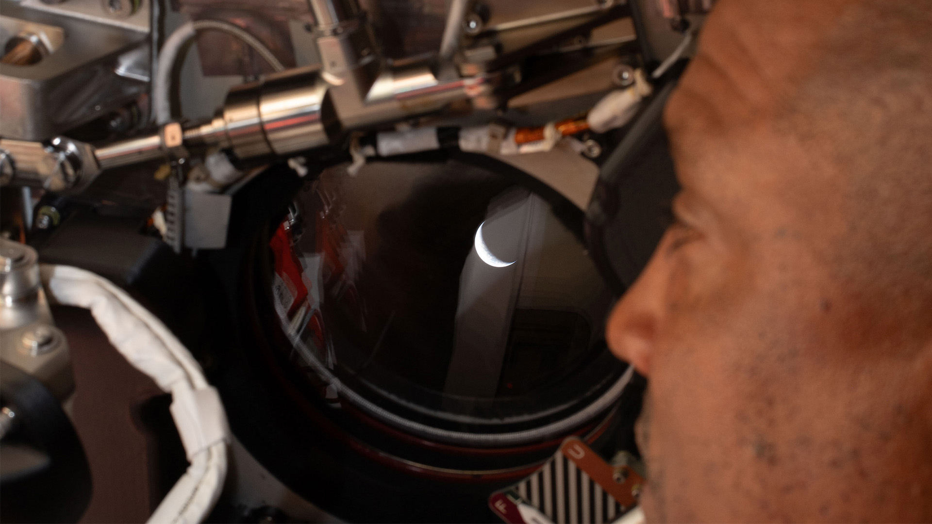 In this photo provided by NASA, Artemis 2 pilot and NASA astronaut Victor Glover looks out one of the windows of the Orion spacecraft and looks back at Earth before the crew flyby of the moon, Monday, April 6, 2026.