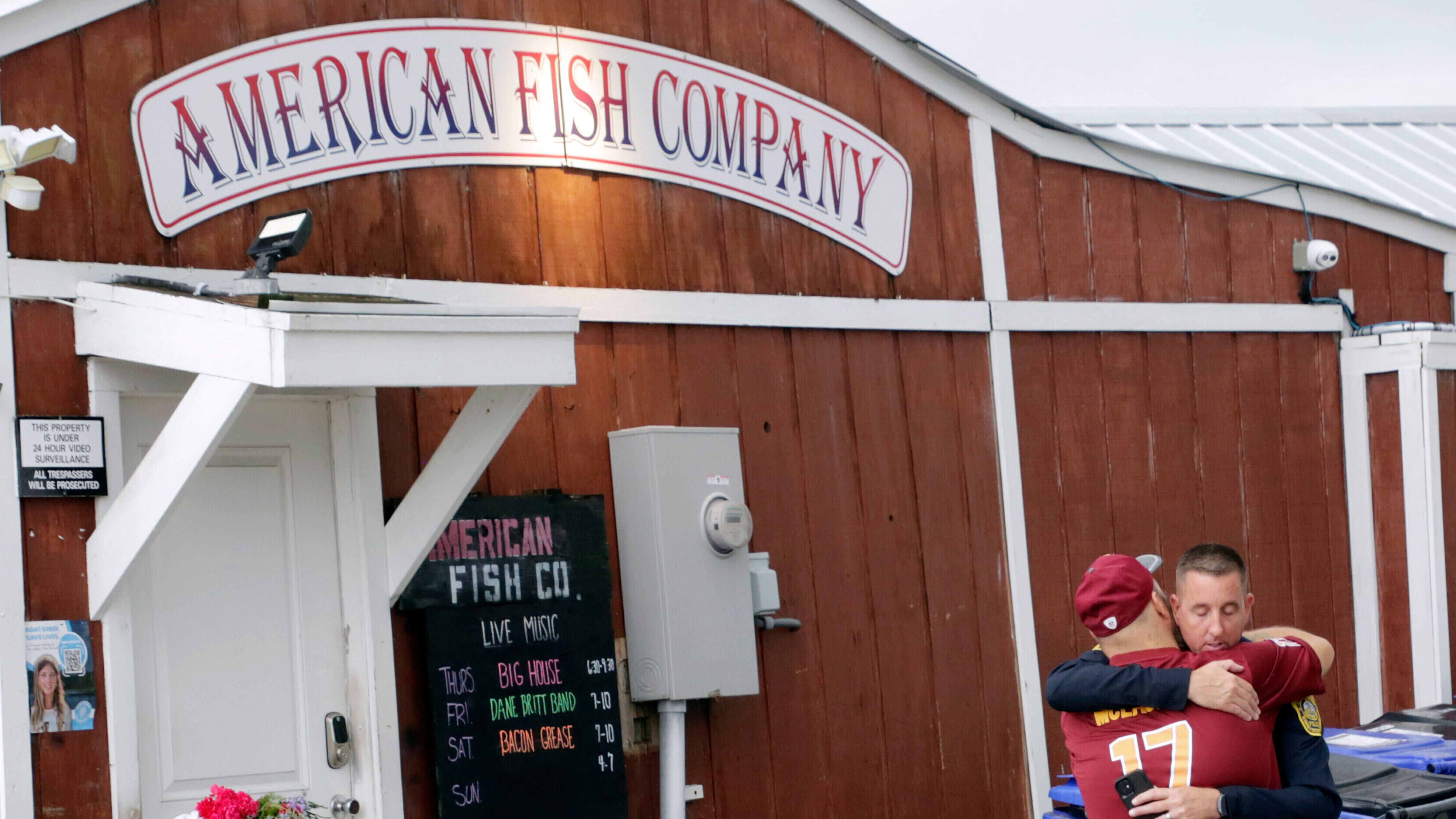A man hugs a police officer in front of the American Fish Company following a fatal shooting that occurred the night before, Sept. 28, 2025, in Southport, N.C.