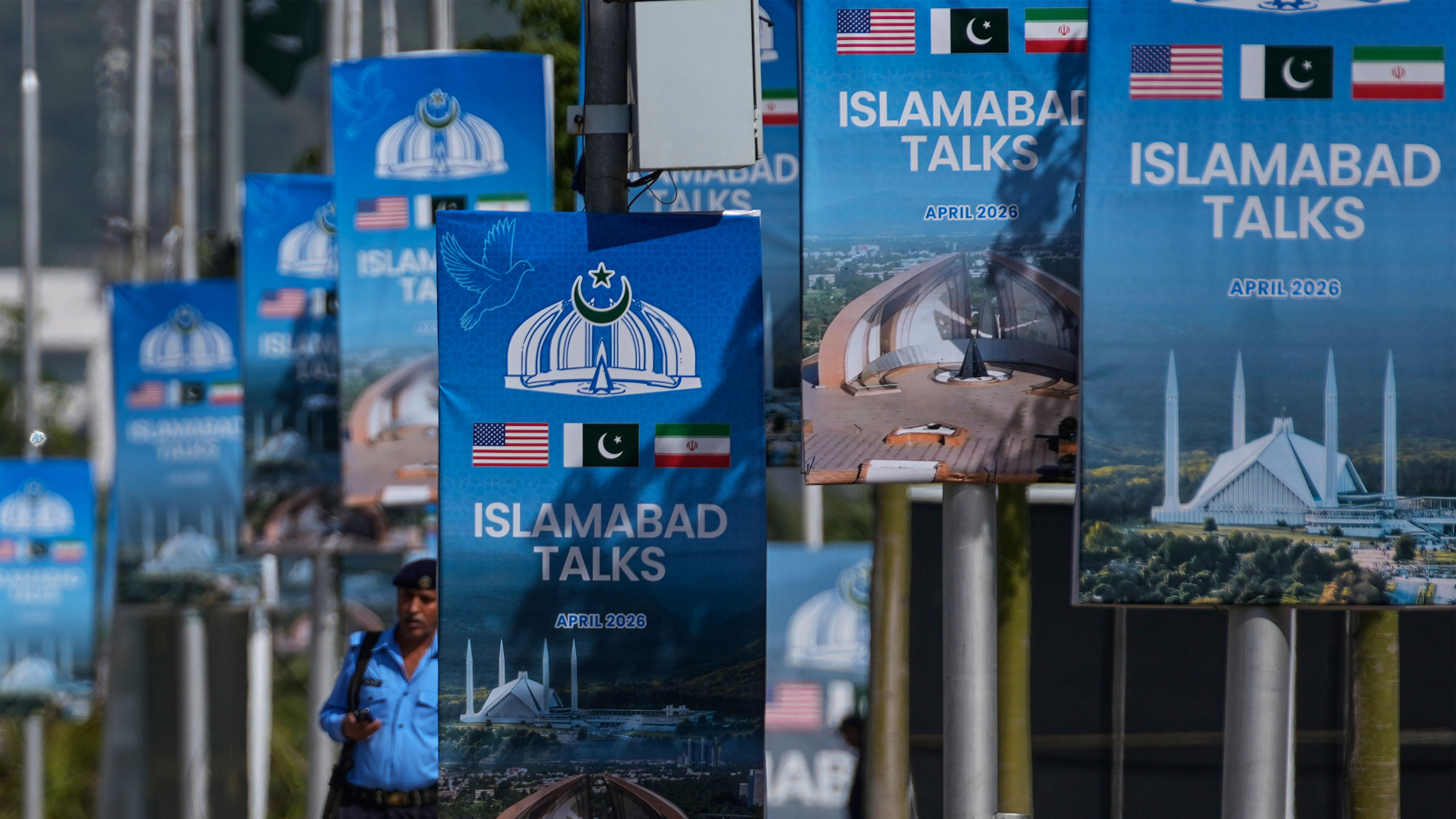 A police officer walks past billboards near the Serena Hotel ahead of the second round of negotiations between the U.S. and Iran, in Islamabad, Pakistan, Tuesday, April 21, 2026.