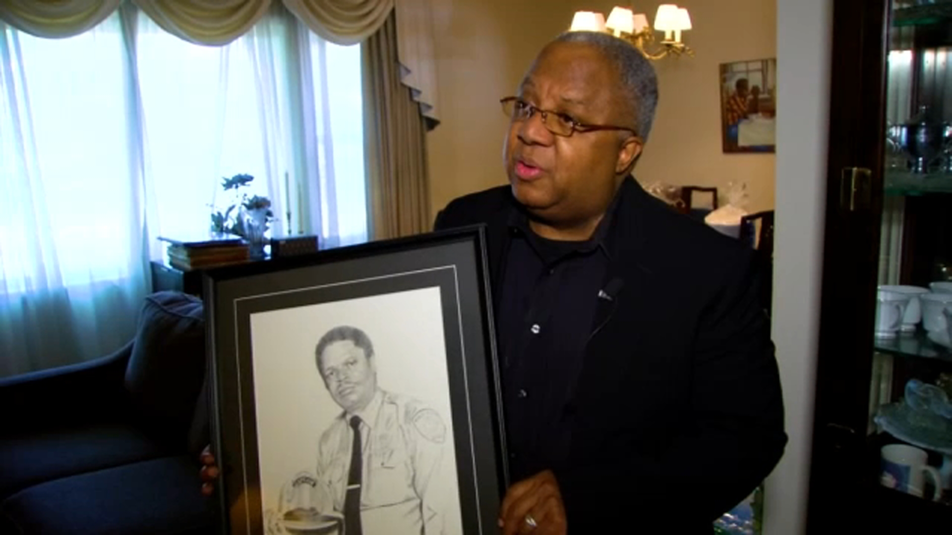 Reginald Lyon holds a portrait of his father.