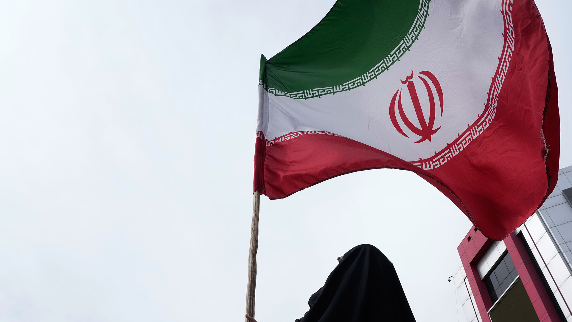 A woman holds an Iranian flag for a pro-government campaign in downtown Tehran, Iran, Saturday, April 25, 2026.