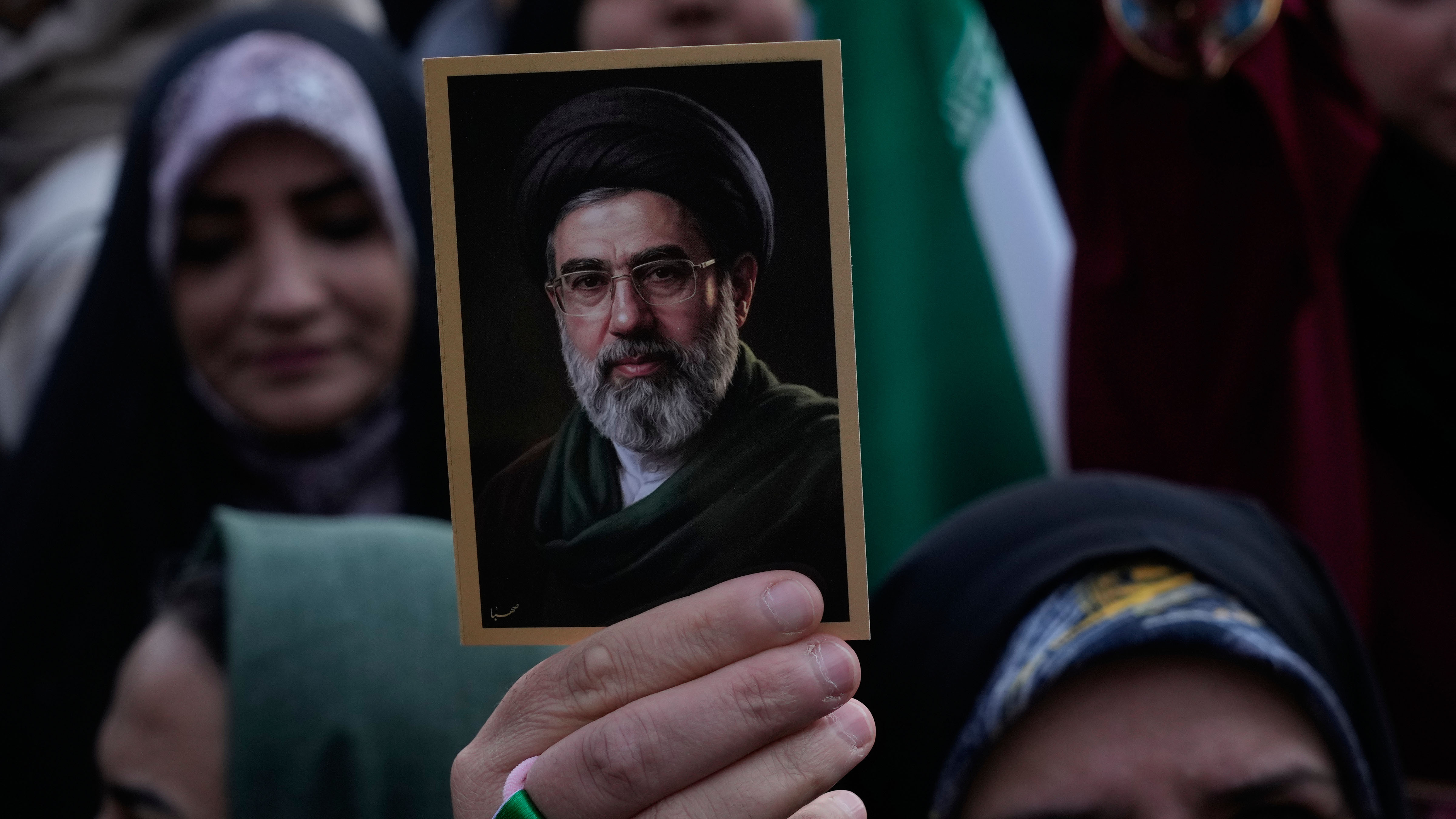 A woman holds up a picture of the Iranian Supreme Leader Ayatollah Mojtaba Khamenei.