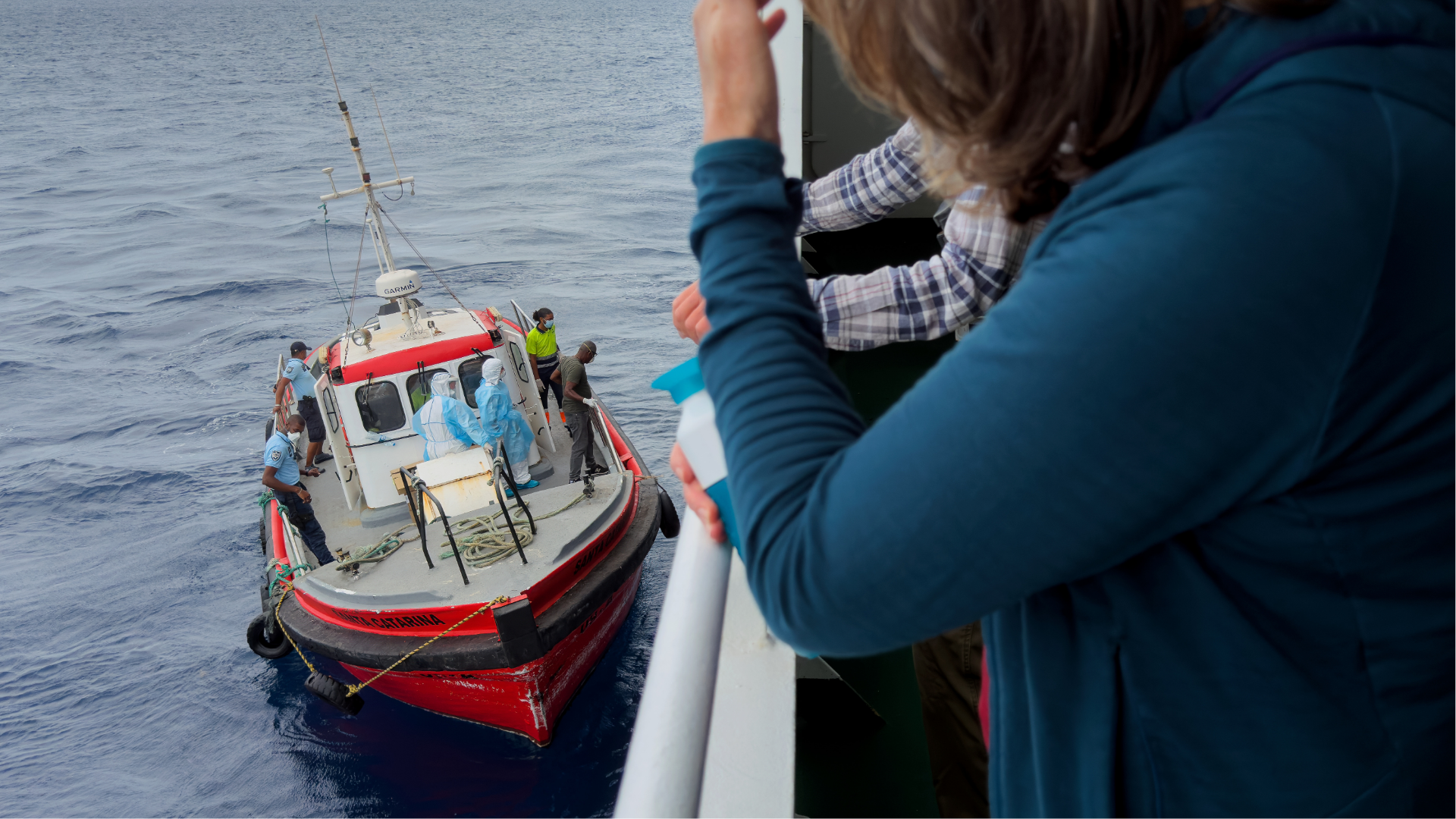 Passengers on the the hantavirus-stricken cruise ship, MV Hondius, watch epidemiologists board the boat in Praia, during their voyage to Spain's port of Tenerife, May 6, 2026.