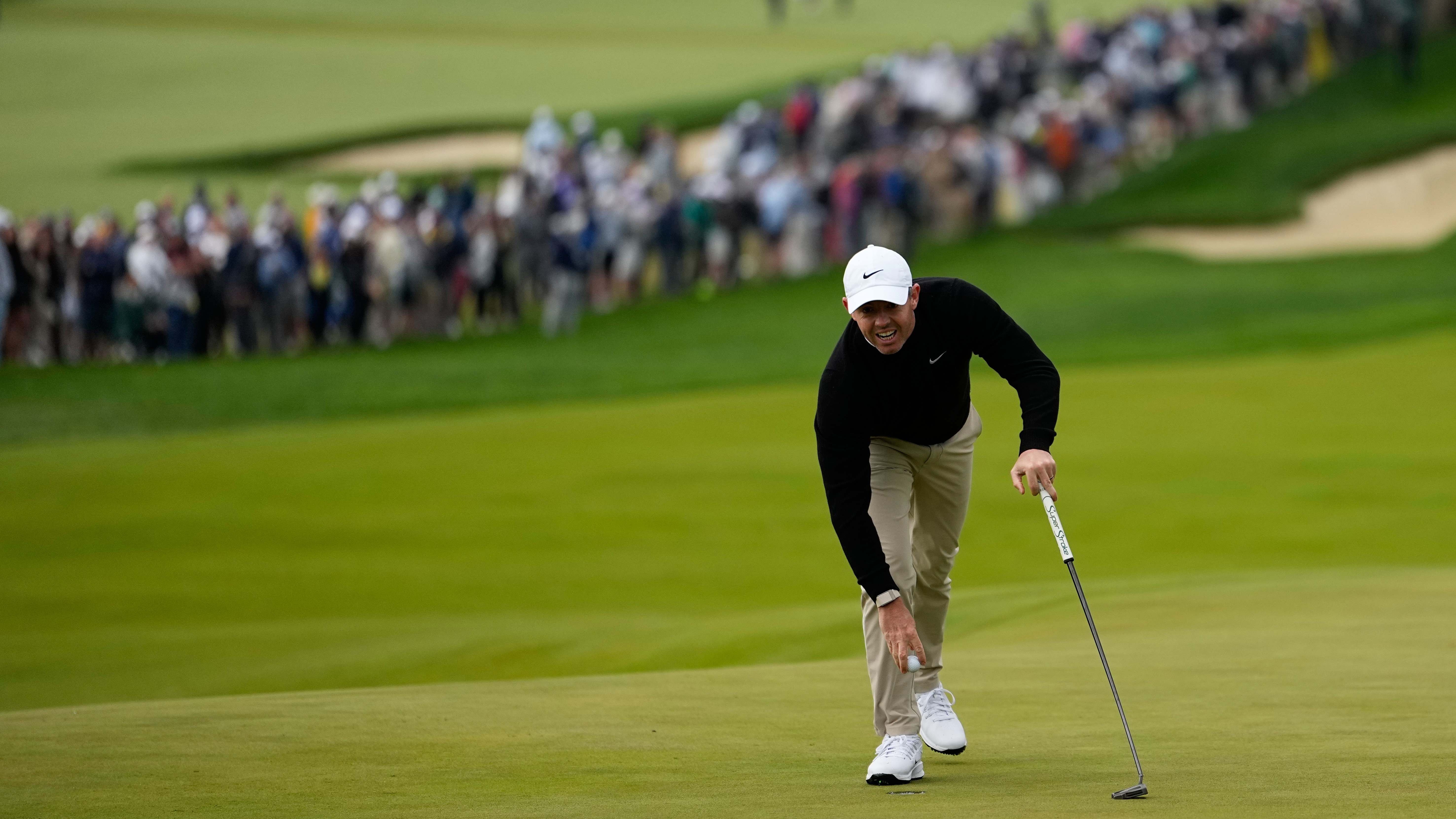 Rory McIlroy retrieves his ball from the 10th green hole during the first round of the PGA Championship at Aronimink Golf Club, Thursday, May 14, 2026, in Newtown Square, PA.