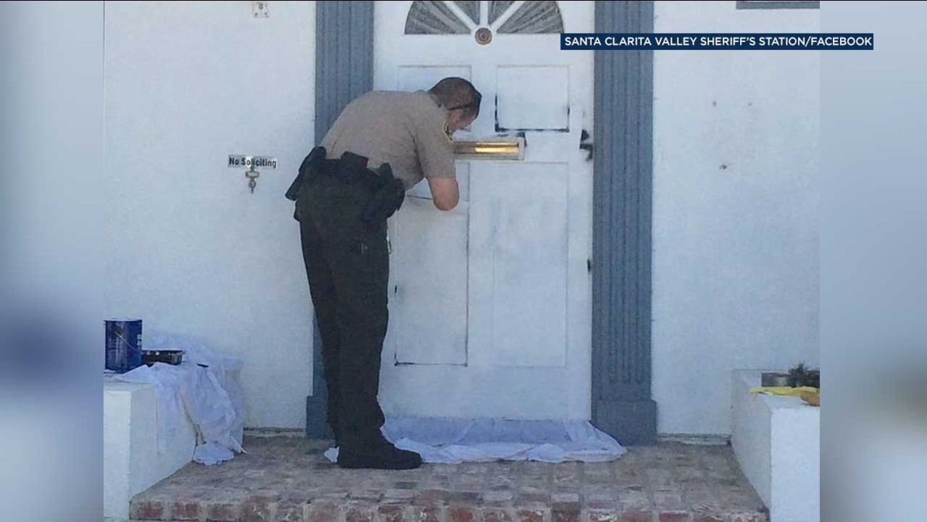 Deputy Scott Peterson is seen painting over graffiti on a door at the home of a Saugus widow in this photo posted to the Santa Clarita Valley Sheriff's Station's Facebook page.