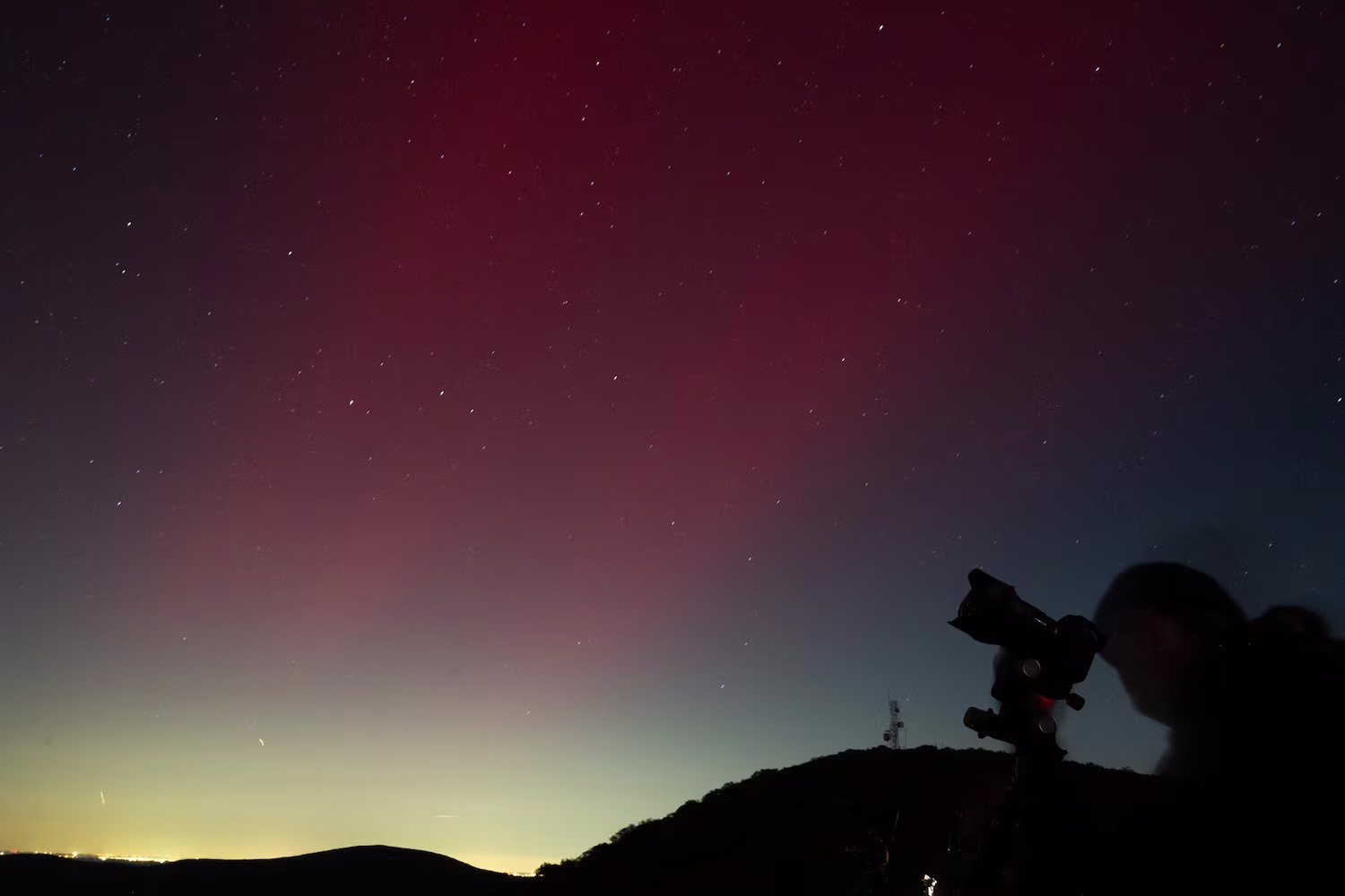 A photographer takes pictures of aurora borealis, or northern lights, produced by a solar geomagnetic storm, seen from Shenandoah National Park in Rileyville, Virginia, on October 10, 2024.