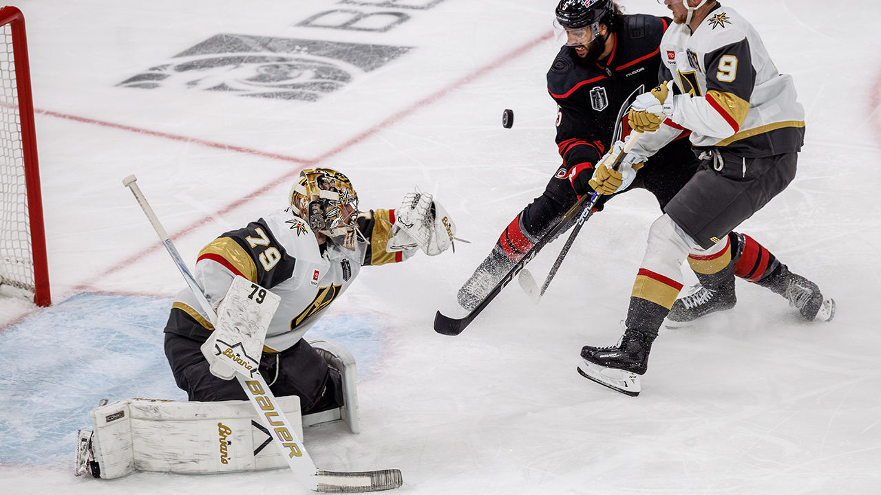 Vegas goalie Carter Hart knocks a puck away from the net as the Hurricanes' Jalen Chatfield battles Jack Eichel during Game 2 on Thursday in Raleigh.
