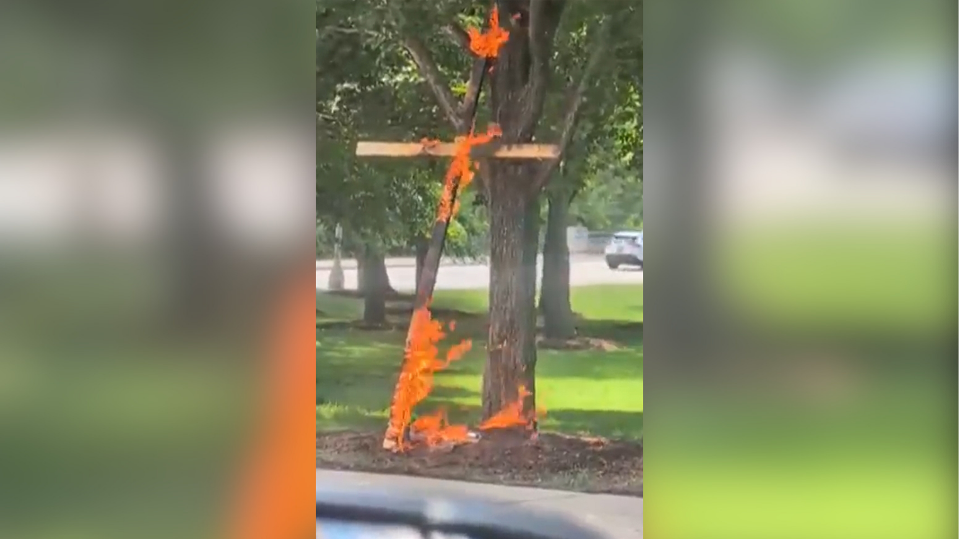 This grab from a video taken by motorist Keinika Carlton shows a wooden cross engulfed in bright orange flames as it leans against a tree in Grant Park, Chicago, Illinois, on Tuesday, July 9, 2026.