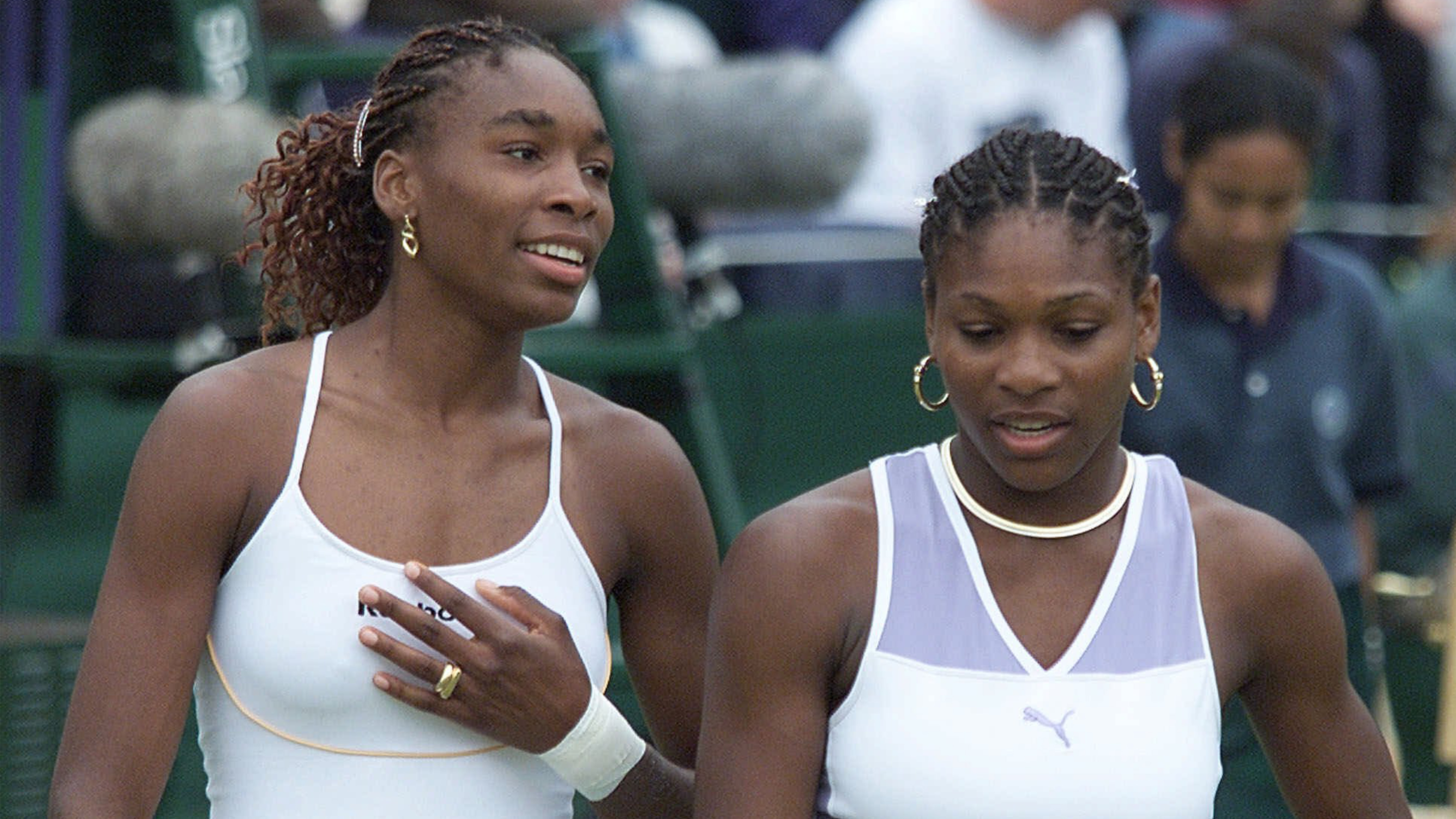 Venus Williams, left, and sister Serena talk together, during their Women's Doubles match against Irina Spirlea and Caroline Vis, at Wimbledon, July 4, 2000.