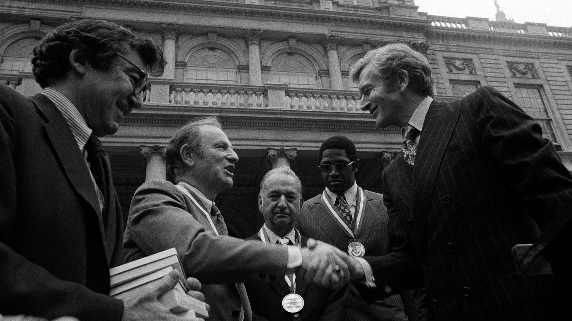 NYC Mayor John Lindsay, right, congratulates Red Holzman, coach of the Knicks, after presenting the city's diamond jubilee medals to the team at City Hall on May 15, 1973.