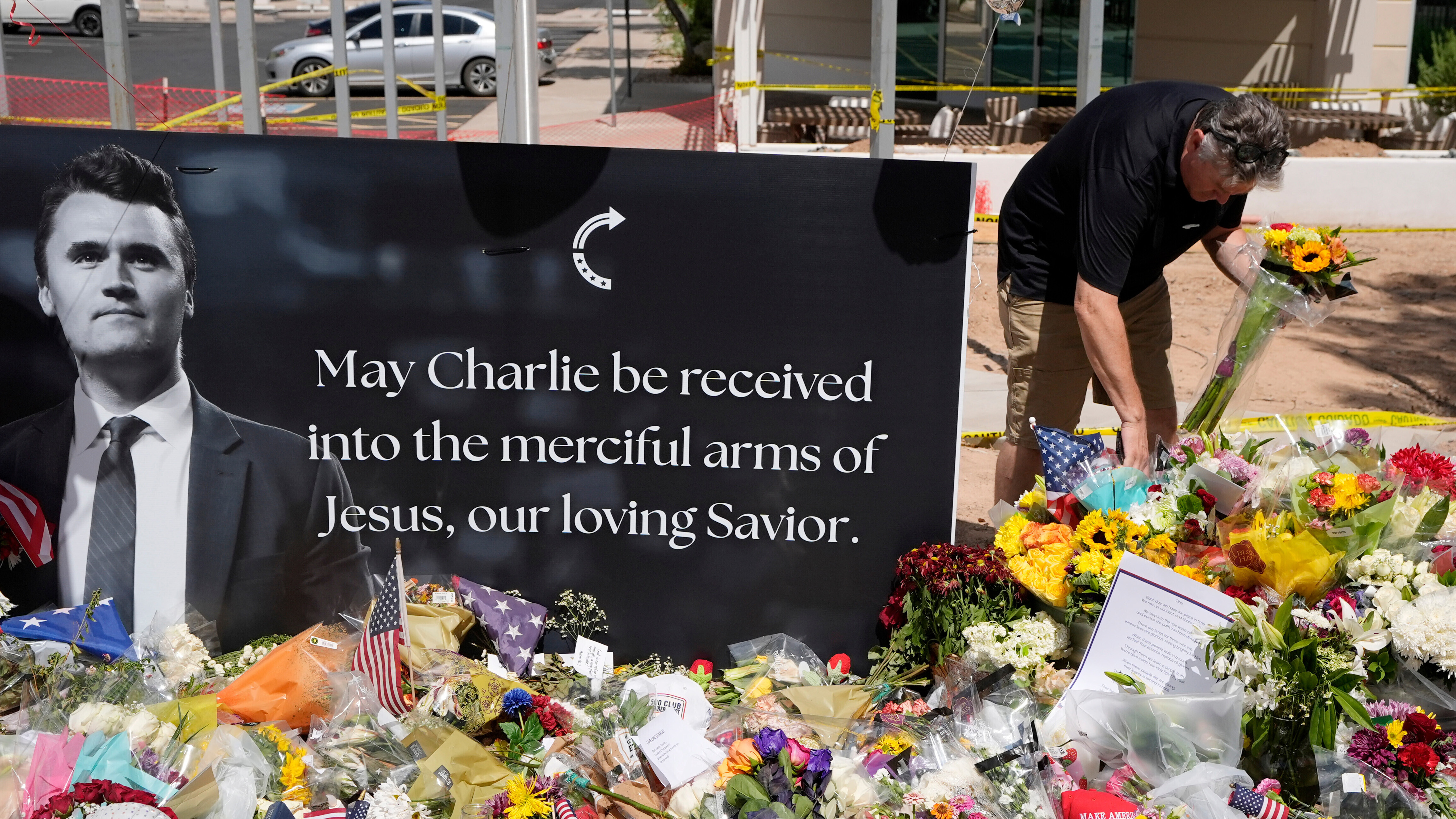A well-wisher places flowers at a makeshift memorial set up for Charlie Kirk at Turning Point USA headquarters, Sept. 11, 2025, in Phoenix.