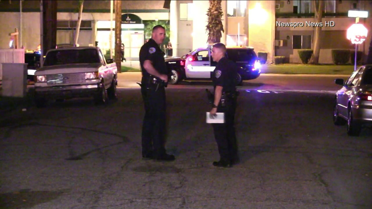 Two San Bernardino police officers confer at the scene of a shooting that left a woman dead in that city on Tuesday, April 2, 2017.
