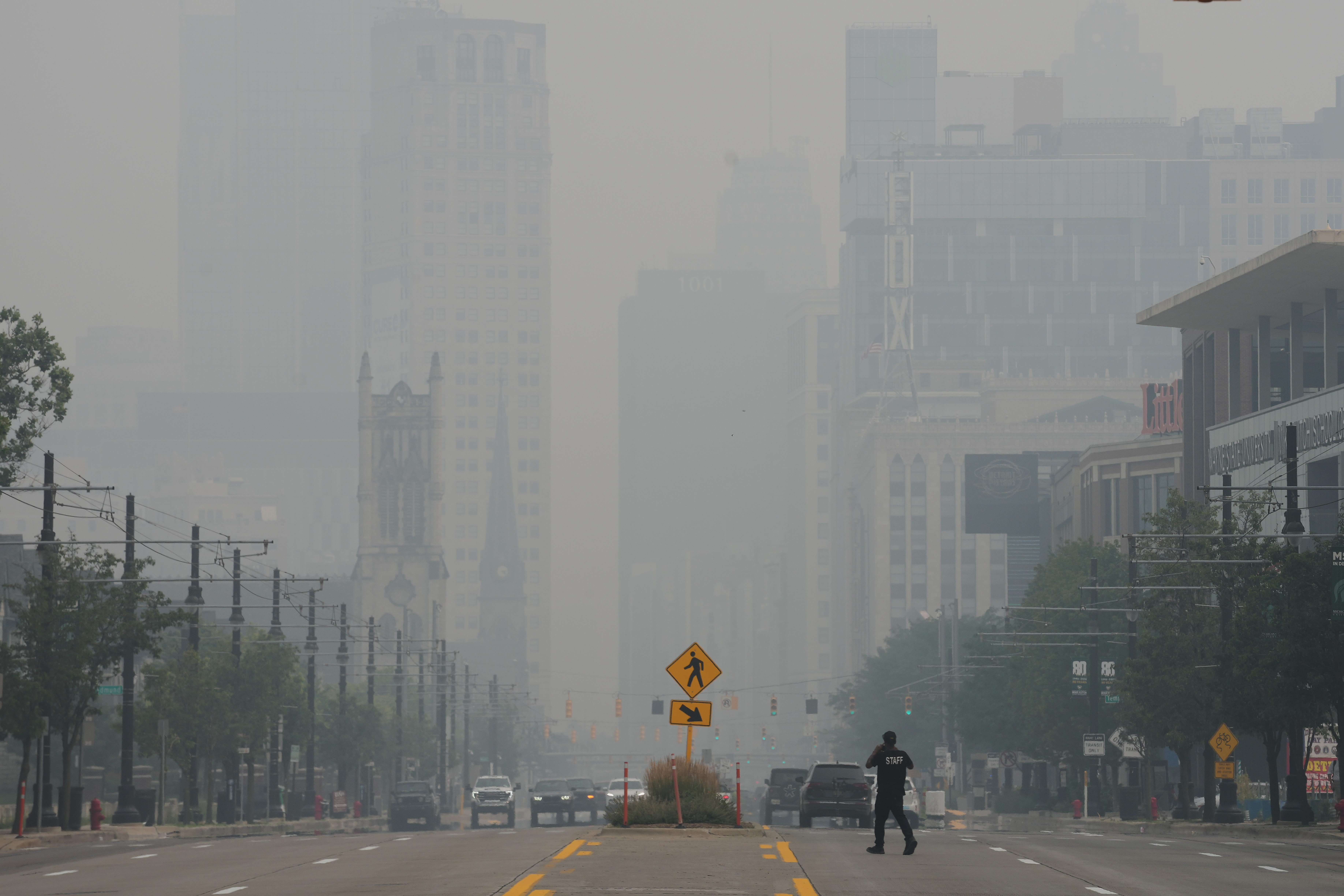 A pedestrian crosses the street as the Detroit city skyline is obscured during poor air quality due to smoke from Canadian wildfires Thursday, July 16, 2026, in Detroit.