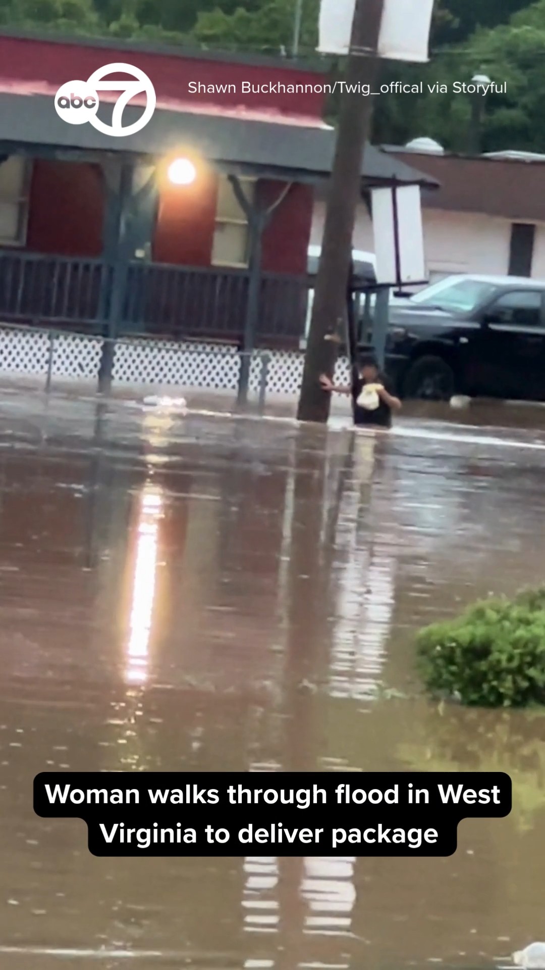 Woman Wades Through Waist-Deep Floodwater to Deliver Package