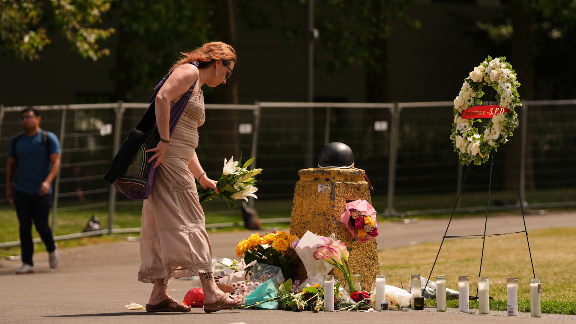 A woman places flowers at a memorial for victims of a July 26 shooting at Seattle Center during the Bite of Seattle food festival, Tuesday, July 28, 2026, in Seattle.