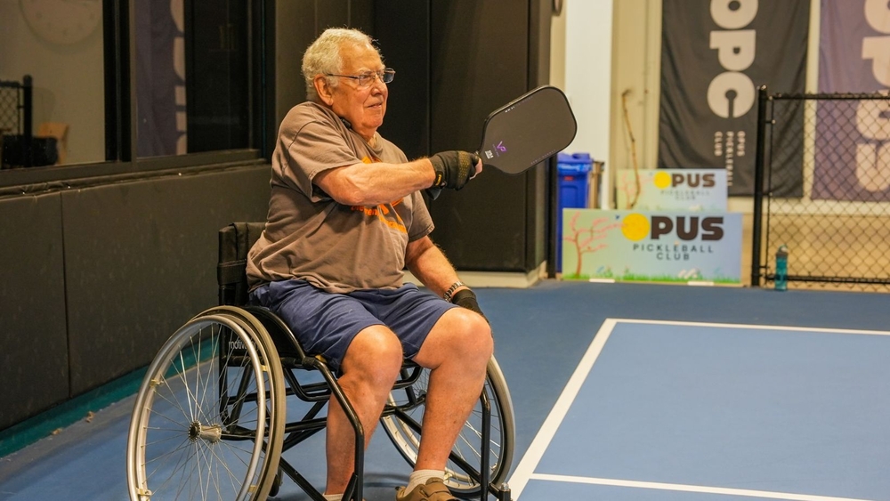 Wheelchair pickleball player swings his paddle with a purpose
