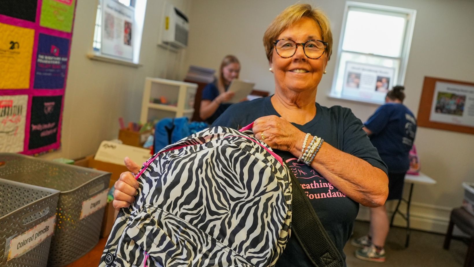 Volunteers pack book bags for families dealing with cancer