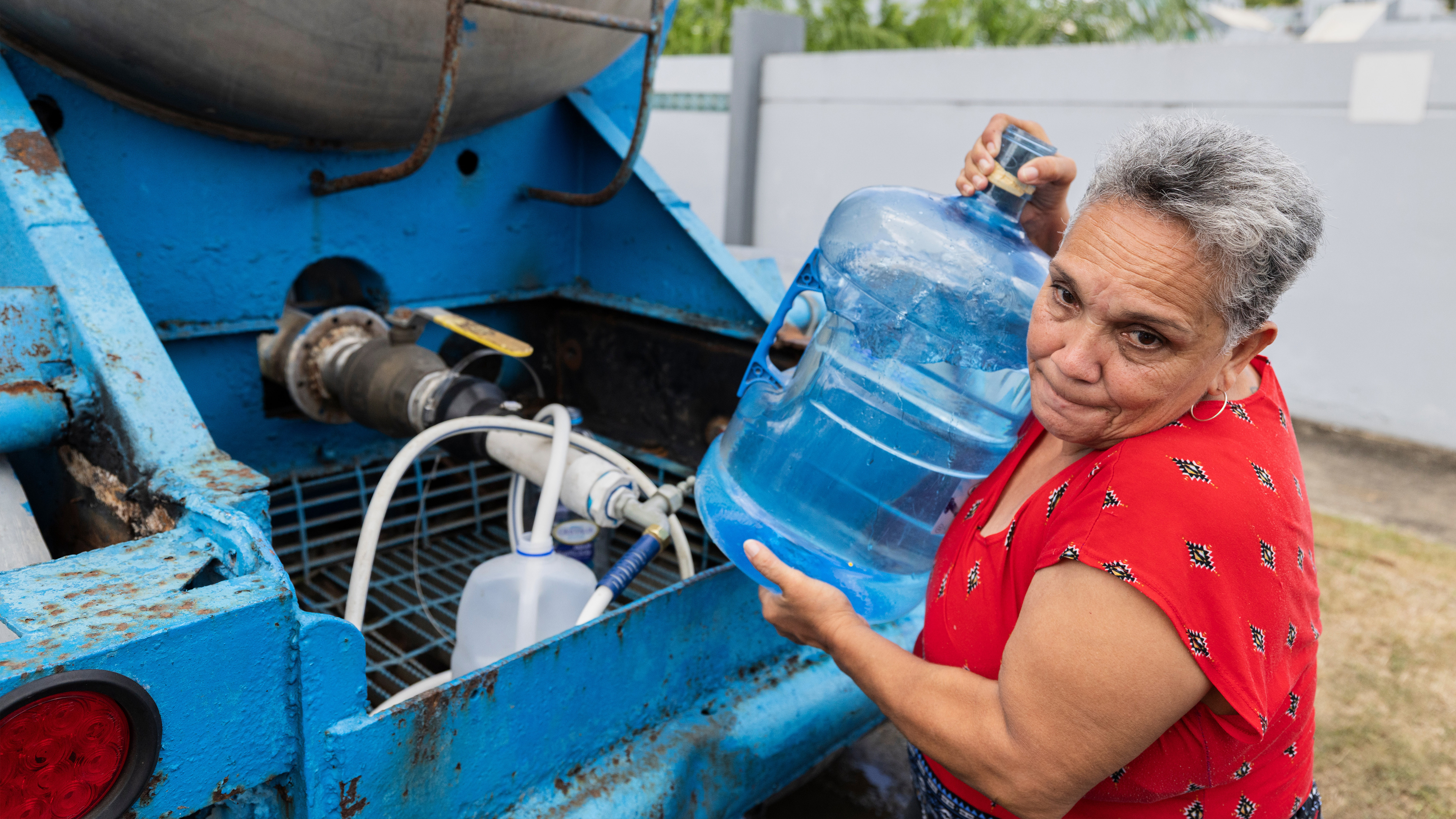 A woman lifts a jug she filled with water from a tanker truck amid rationing caused by drought, in the Cupey sector of San Juan, Puerto Rico, Wednesday, Aug. 5, 2026. 