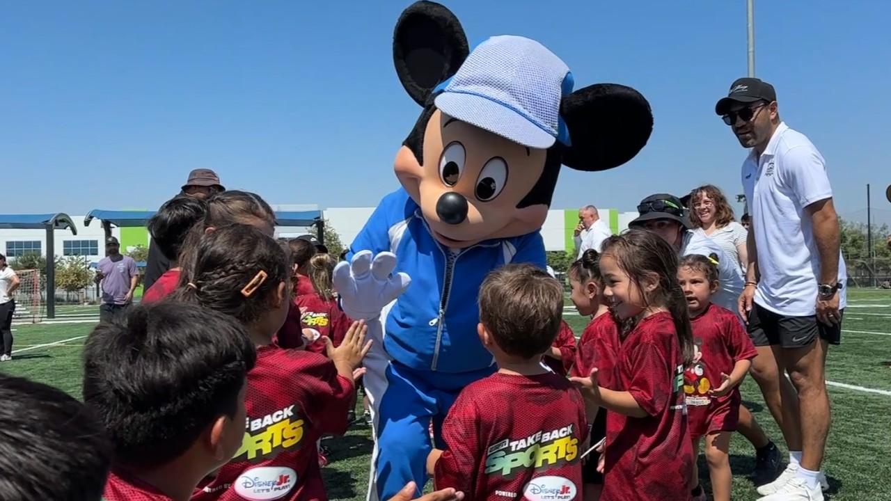 Young players surprised by Mickey Mouse on Fontana soccer field