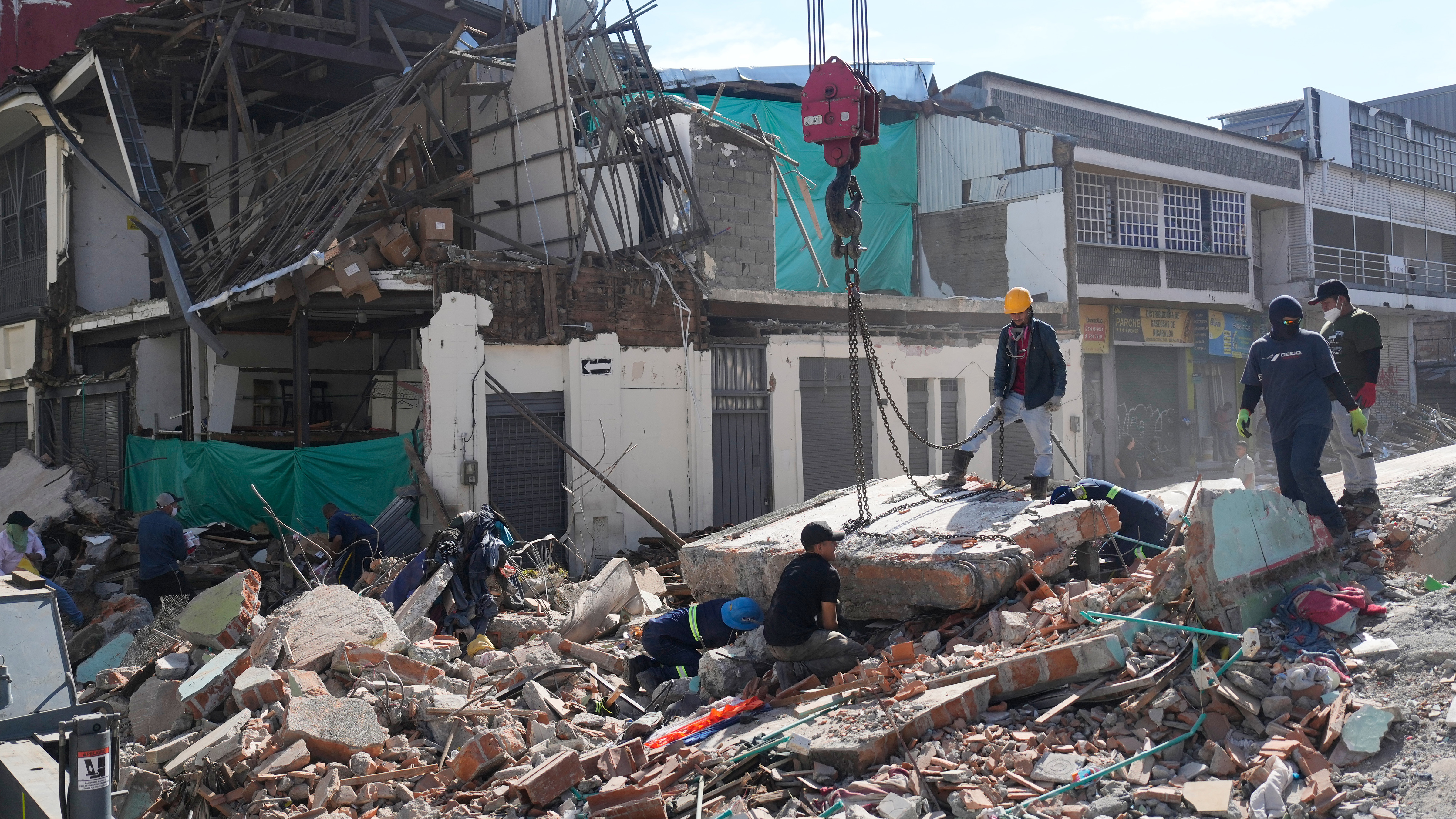 Workers secure a section of the collapsed structure with chains before it is lifted by a crane the day after an earthquake struck Pereira, Colombia, Tuesday, Aug. 11, 2026.