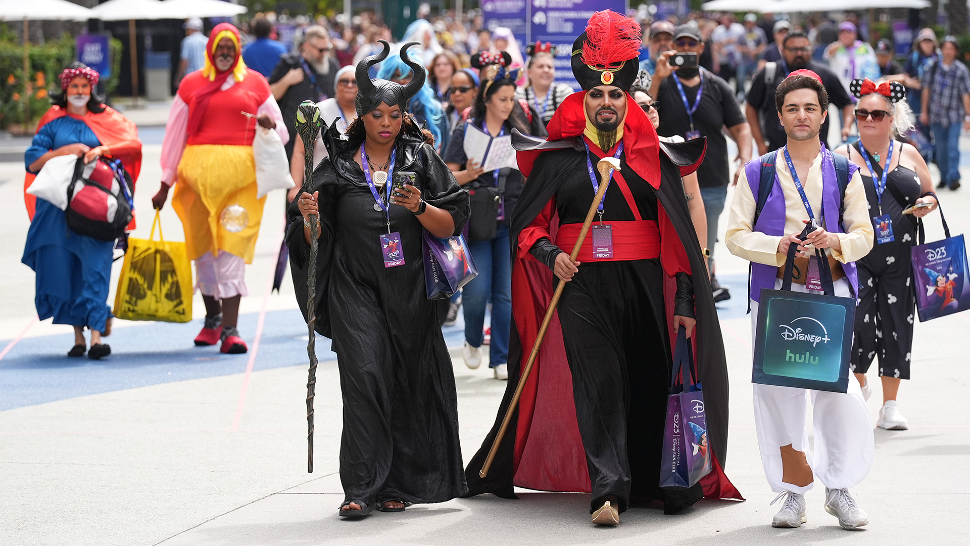 Cosplayers dressed as Maleficent, left, and Jafar, center, and Aladdin arrive for D23 on Aug. 14, 2026 in Anaheim, Calif.