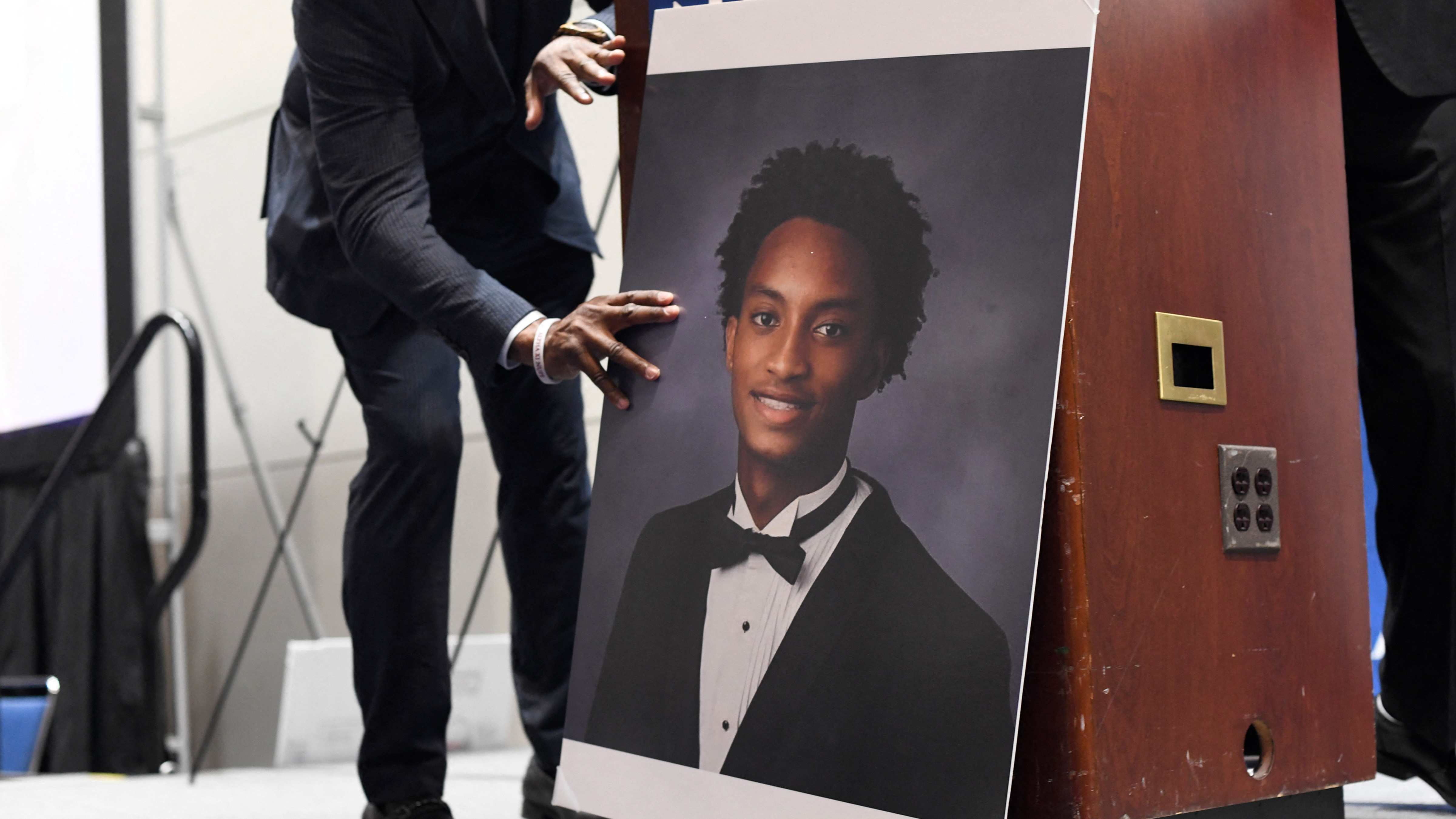 A man places a photograph of Nolan Xavier Wells in front of the podium before a news conference during the 117th NAACP National Convention at McCormick Place in Chicago, Illinois, on July 22, 2026.