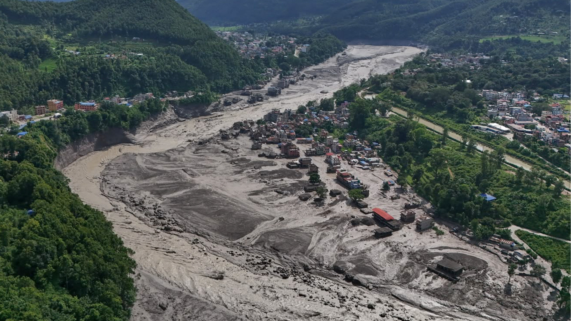 Damaged houses stand precariously near the swollen, debris-choked banks of the Trishuli River after flash floods in Nepal's Nuwakot district on Wednesday, Aug. 26, 2026.