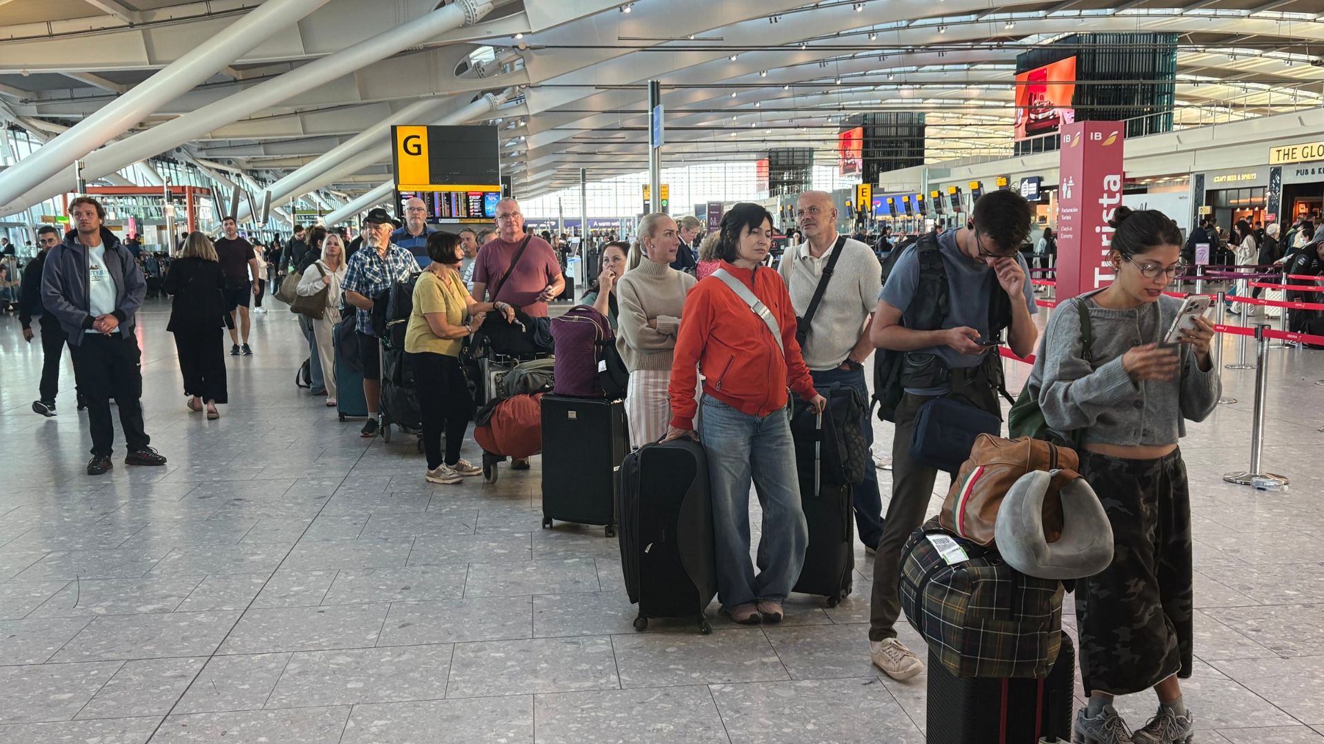 Passengers wait in line at Heathrow Airport in London, during an air traffic control problem that disrupted travel across Britain.