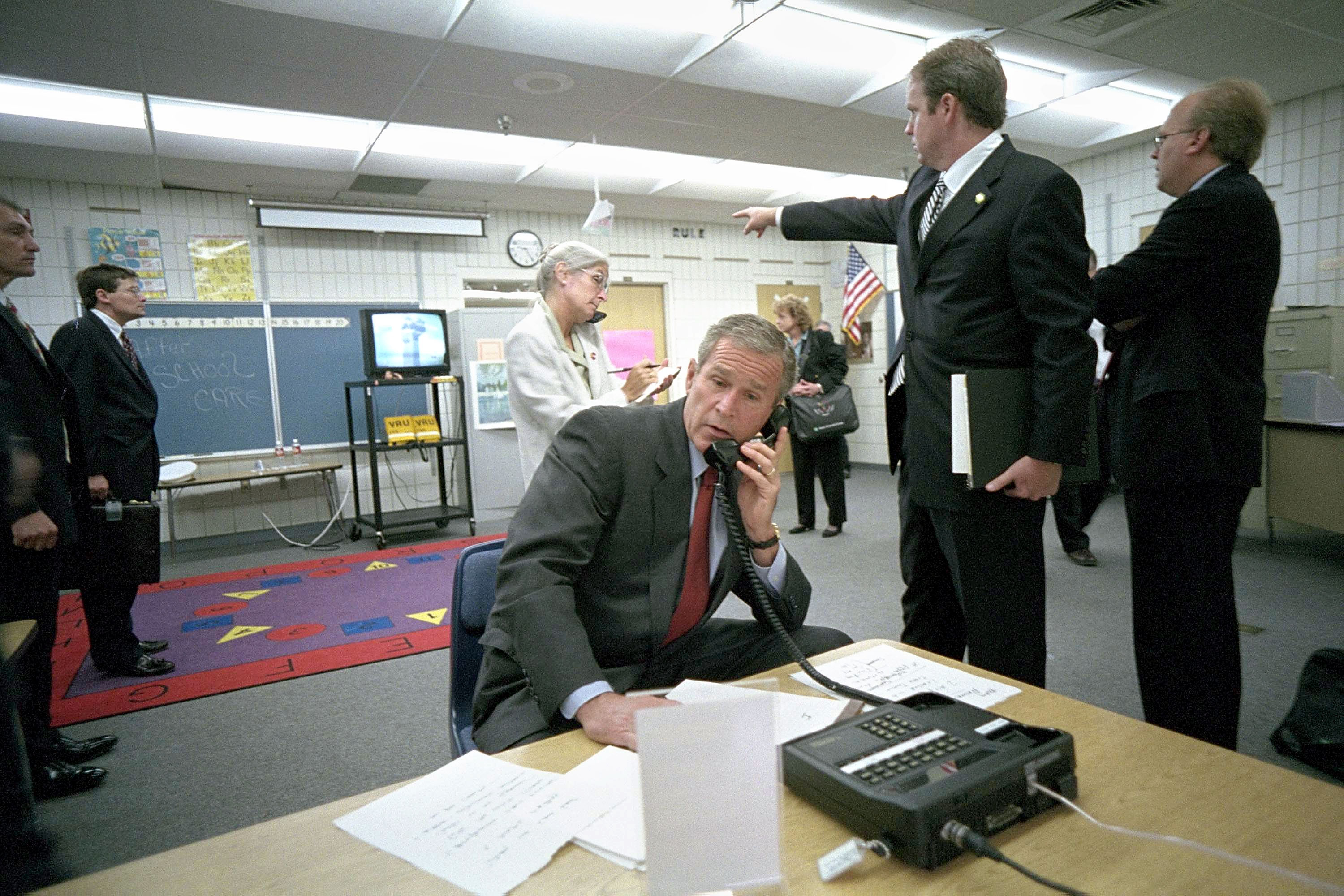 President George W. Bush makes a telephone call as White House Director Of Communications Dan Bartlett points to video footage of the terrorist attack on the World Trade Center from Emma Booker Elementary School September 11, 2001 in Sarasota, Florida.