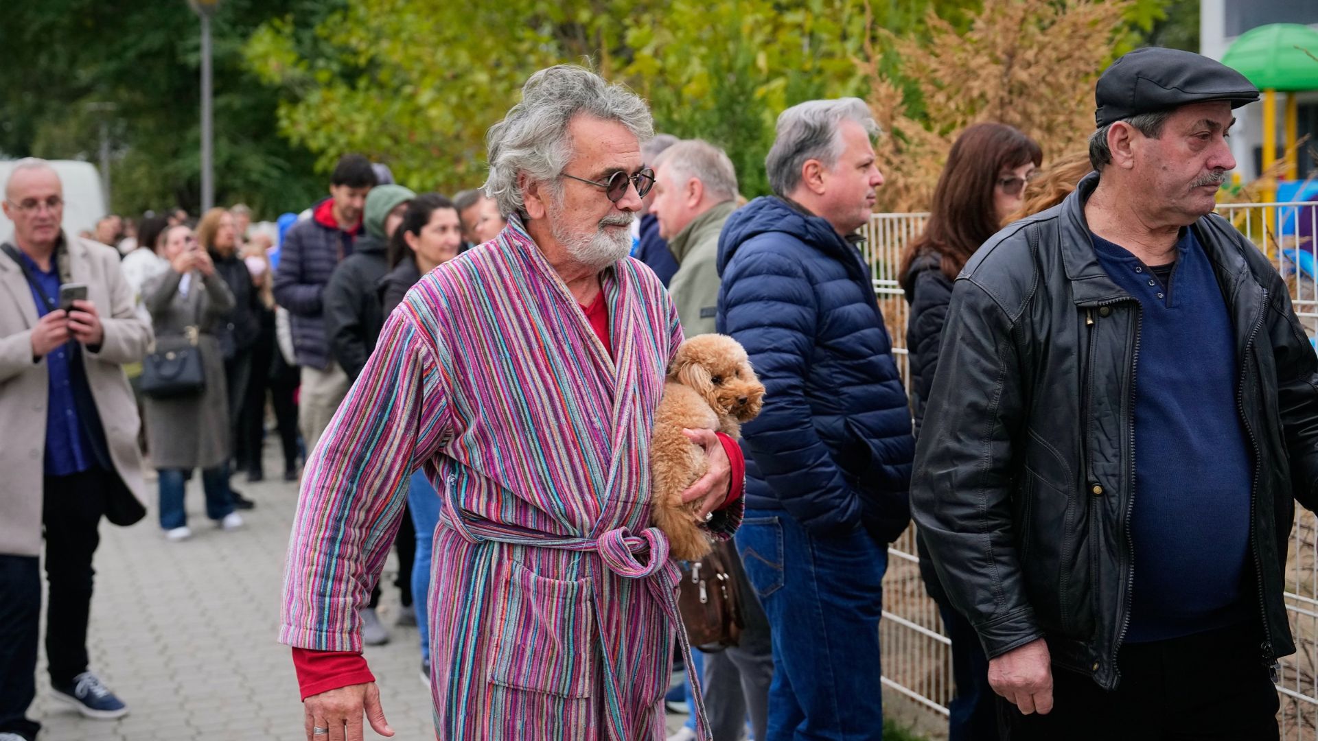 A man holds a dog while arriving at a polling station to vote in a parliamentary election in Belgrade, Serbia, Sunday, Oct. 25, 2026.