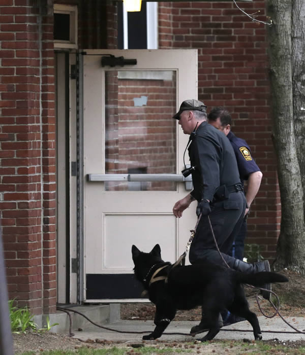 A police officer enters an apartment building with his dog while searching for a suspect in the Boston Marathon bombings in Watertown, Mass., Friday, April 19, 2013. The bombs that blew up seconds apart near the finish line of the Boston Marathon left the streets spattered with blood and glass, and gaping questions of who chose to attack and why.