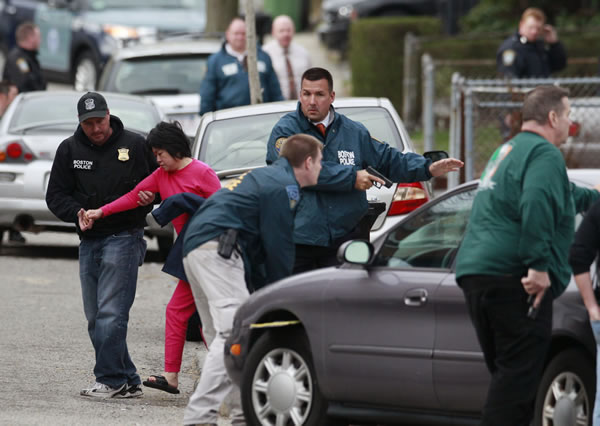 A neighbor is escorted to safety as police surround a home while searching for a suspect in the Boston Marathon bombings in Watertown, Mass., Friday, April 19, 2013. The two suspects in the Boston Marathon bombing killed an MIT police officer and hurled explosives at police in a car chase and gun battle overnight that left one of them dead and his brother on the loose, authorities said Friday.