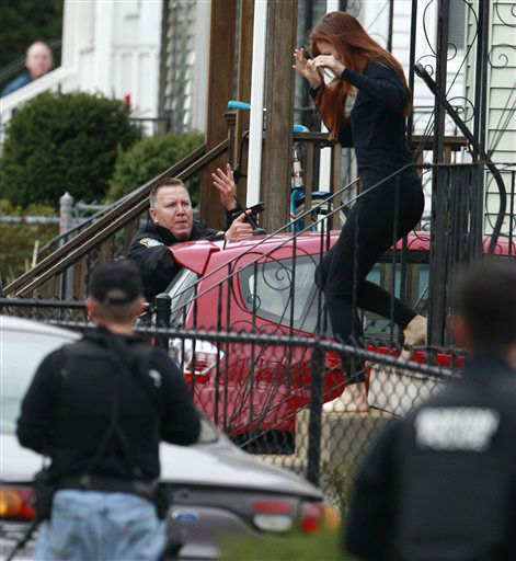 A barefooted woman runs for cover as police surround a home while searching for a suspect in the Boston Marathon bombings in Watertown, Mass., Friday, April 19, 2013.