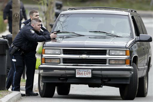 Police officers take cover as they conduct a search for a suspect in the Boston Marathon bombings, Friday, April 19, 2013, in Watertown, Mass.