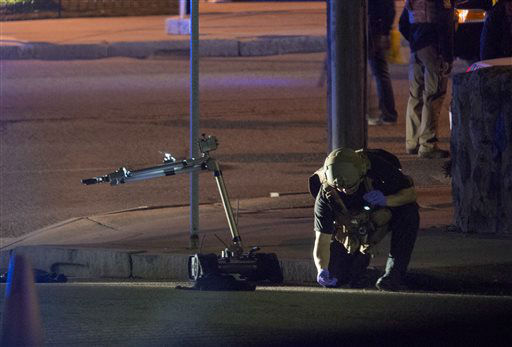 A Police official looks over object that was picked up by a remote control device, left, as they investigate an incident in Friday, April 19, 2013, in Watertown, Mass.
