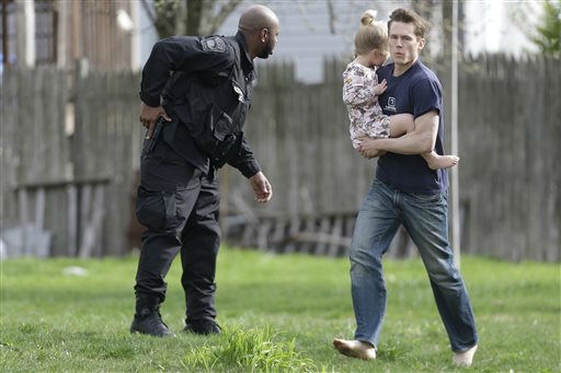 A police officer evacuates a shoeless man holding a child as members of law enforcement conduct a search for a suspect in the Boston Marathon bombings, Friday, April 19, 2013, in Watertown, Mass.