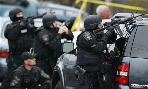 Police in tactical gear surround an apartment building while looking for a suspect in the Boston Marathon bombings in Watertown, Mass., Friday, April 19, 2013.