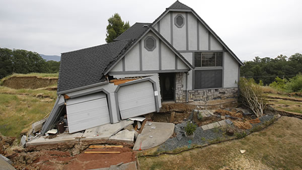 This photo taken Monday, May 6, 2013 shows the wreckage of the Tudor-style dream home of Robin and Scott Spivey who were forced to abandon after the ground gave way causing it to drop 10 feet below the street in Lakeport, Calif. Officials believe that water that has bubbled to the surface is playing a role, in the collapse of the hillside subdivision that has forced the evacuation of 10 homes and the notice of imminent evacuation of another 10 in this upscale subdivision.(AP Photo/Rich Pedroncelli)