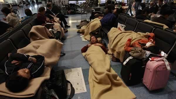 Travelers rest on the floor stranded at the Haneda international airport in Tokyo after a massive earthquake Friday, March 11, 2011. The ferocious tsunami spawned by one of the largest earthquakes ever recorded slammed Japan's eastern coasts. (AP Photo/Wally Santana)