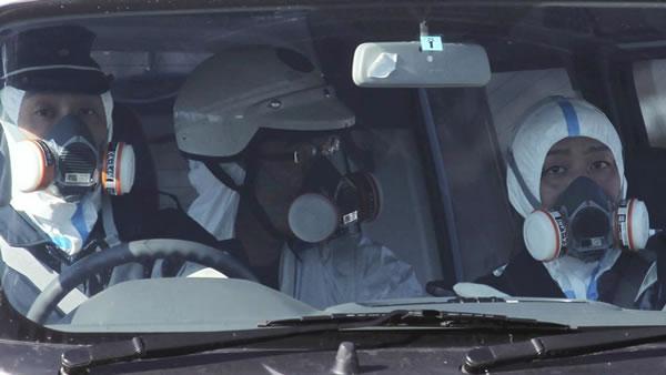 Police officers wearing gas masks patrol in the area of the Fukushima power plant's Unit 1 in Okumamachi, Fukushima Prefecture (state), northern Japan, Saturday, March 12, 2011, amid fears that a part of the plant could meltdown after being hit by a powerful earthquake and tsunami Friday. (AP Photo/The Yomiuri Shimbun, Kaname Yoneyama)