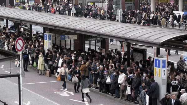 Commuters wait in a long queue at a bus terminal outside Yokohama railway station in Yokohama, southwest of Tokyo, following a strong earthquake hit eastern Japan on Friday, March 11, 2011.